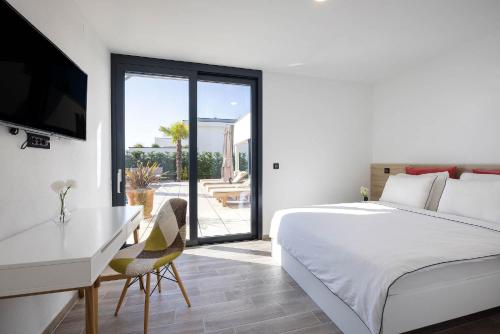 a bedroom with a bed and a desk and a television at FIRST RESIDENCE Villa Eternity in Linardići