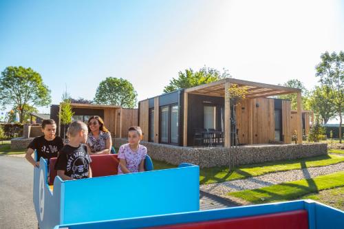 a family riding a roller coaster in front of a tiny house at EuroParcs Poort van Maastricht in Berg en Terblijt