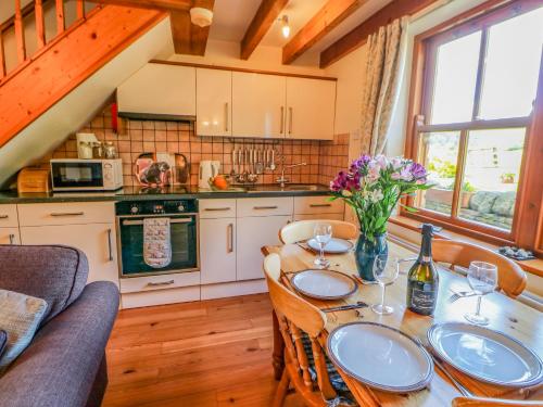 een keuken met een tafel met wijnglazen en bloemen bij Moorgair Cottage in Slaley