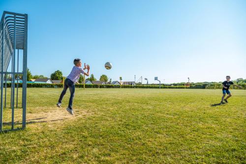 two young men playing soccer on a field at EuroParcs Poort van Maastricht in Berg en Terblijt