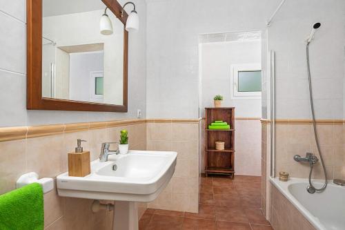 a bathroom with a sink and a tub and a mirror at Villa Mercedes by Villa Plus in Cala en Forcat