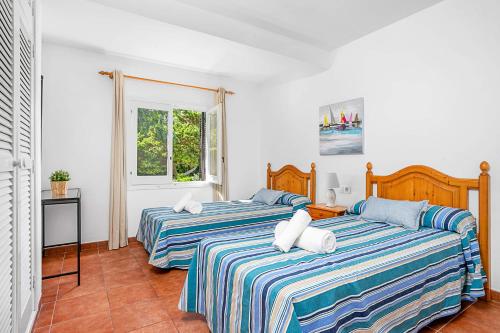 two beds in a white room with two at Villa Mercedes by Villa Plus in Cala en Forcat