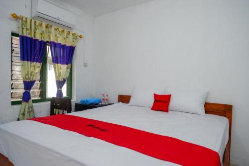 a bedroom with a bed with a red blanket on it at RedDoorz Syariah @ Ndalem Kembang Sore Yogyakarta in Timuran