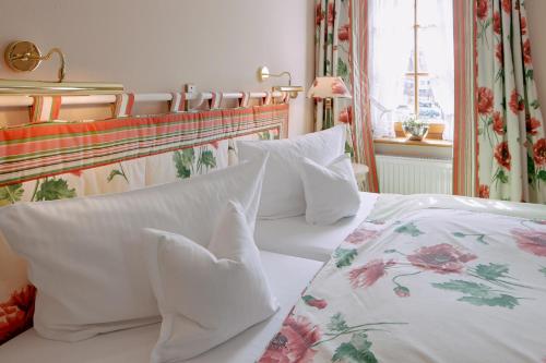 a bedroom with a bed with white sheets and pillows at Romantik Hotel & Restaurant Hirsch in Sonnenbühl