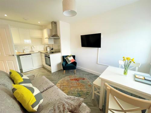 a living room with a couch and a table and a kitchen at Modern 2 Bed Apt Centre Of Penzance, Lift Access in Penzance