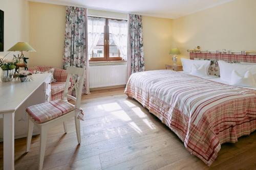 a bedroom with a bed and a desk and a window at Romantik Hotel & Restaurant Hirsch in Sonnenbühl