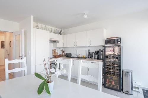 une cuisine avec des armoires blanches et un réfrigérateur noir dans l'établissement À portée de mer. Appt 70m2, 2ch+parking, à Wimereux