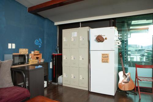 a room with a white refrigerator and a guitar at Corner Hostel & Cafe in Taipei