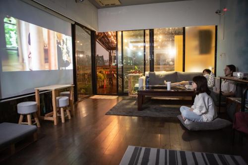 a woman sitting on a chair in a living room at Corner Hostel & Cafe in Taipei