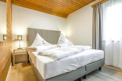 um quarto com uma cama com lençóis brancos e uma janela em First Apartment em Grindelwald