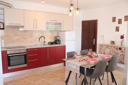 una cucina con armadi rossi e un tavolo con sedie di Apartments KIKASO - Near Mall of Split, free parking a Spalato (Split)