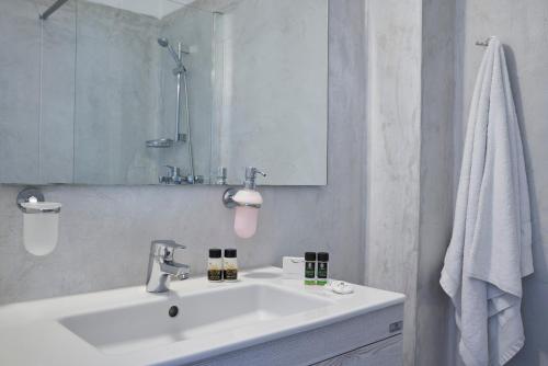 a white bathroom with a sink and a mirror at Polos Hotel Paros in Parikia