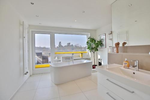 een witte badkamer met een wastafel en een groot raam bij Strandallee 10 Penthouse Seaview in Haffkrug