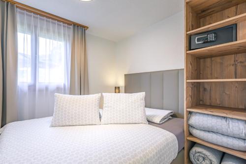 a bedroom with a bed with white pillows and a window at Chalet Graben - Aare Jungfrau AG in Grindelwald