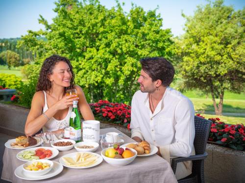 a man and a woman sitting at a table with food at Active Hotel Paradiso in Peschiera del Garda