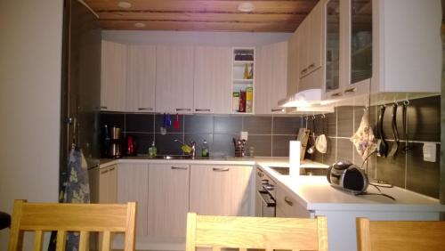 una cocina con armarios blancos y azulejos negros en la pared en Revontuli Cottage, en Kolari