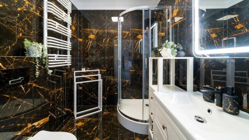 a bathroom with a black and gold marble wall at HELLO Apartamenty - Pohulanka w sercu Karpacza in Karpacz