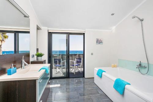 a bathroom with two sinks and a tub with a view of the ocean at Villa Sea View by Villa Plus in Sa Caleta