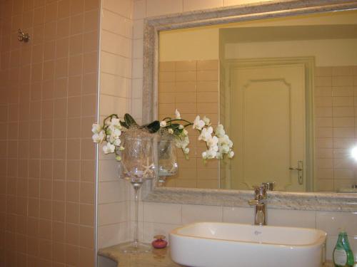 un bagno con lavandino, specchio e vaso con fiori di B&B Ristorante del Monte a Colleretto Giacosa