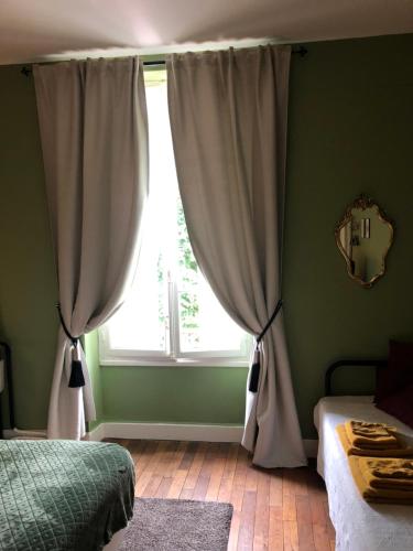 a bedroom with a window with curtains and a bed at Maison de la Comtesse in Cosne-dʼAllier