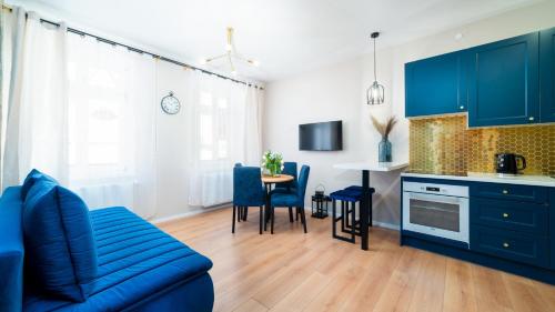a living room with a blue couch and a kitchen at HELLO Apartamenty Evo - Długa 15 in Jelenia Góra