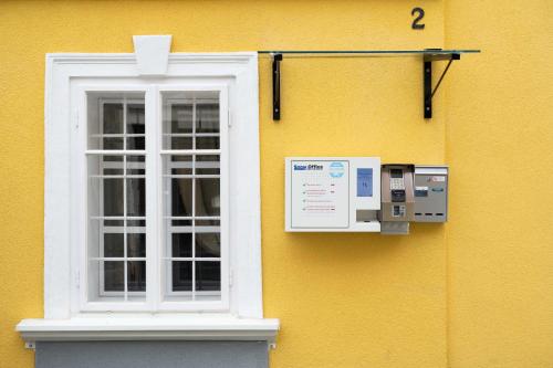 a yellow building with a window and a thermostat at Smarthotel Völkermarkt in Völkermarkt