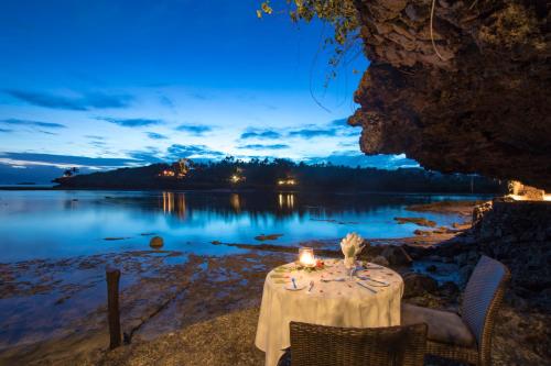 a table with candles on the shore of a lake at Savasi Island Resort in Savusavu
