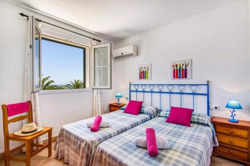 een slaapkamer met 2 bedden met roze kussens en een raam bij Villa Laurel by Villa Plus in Alaior