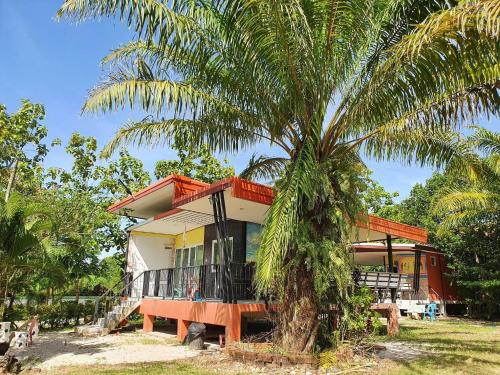 a house with a palm tree in front of it at สิชล บ้านอุ๊ รีสอร์ท in Sichon