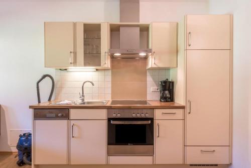 a kitchen with white cabinets and a sink and a refrigerator at Ferienparadies Sabina Puflatsch in Alpe di Siusi