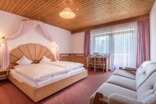 - une chambre avec un grand lit et un canapé dans l'établissement Ferienparadies Sabina Puflatsch, à Alpe di Siusi