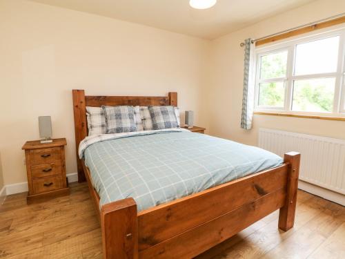 a bedroom with a wooden bed and a window at Brookside in Hayfield