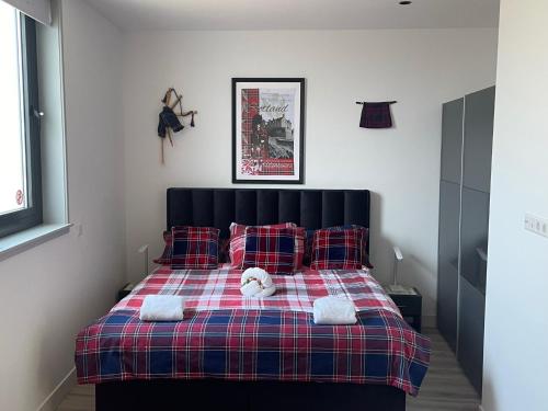 een slaapkamer met een bed met een geruite deken en kussens bij Scottish Thistle in Zandvoort