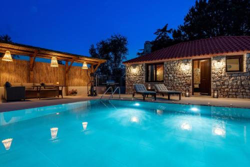 a swimming pool in front of a house at Filerolia Stone House in Pastida