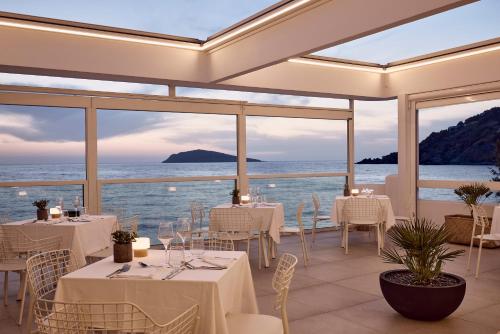 a restaurant with white tables and chairs and the ocean at Kantouni Beach Boutique Hotel in Panormos Kalymnos