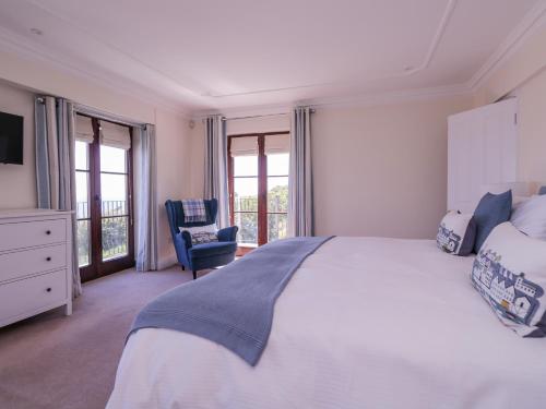 a bedroom with a bed and a chair and windows at Pentire House in Deal