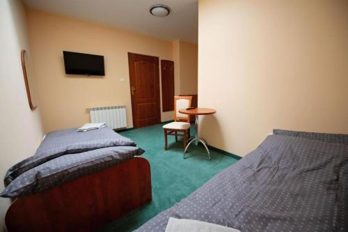 a bedroom with two beds and a table and a television at Pokoje Horyzont in Jarosław