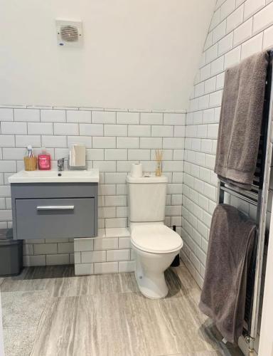 a white bathroom with a toilet and a sink at Romantic hideaway, seconds away from Perran beach in Perranporth