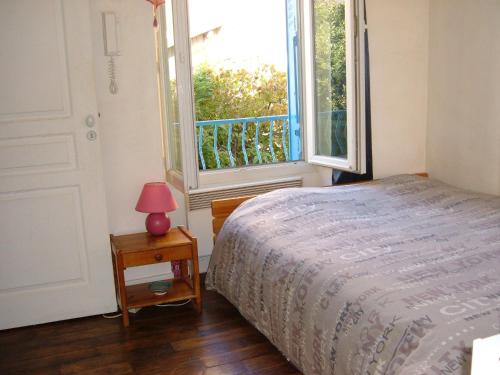 um quarto com uma cama e uma grande janela em Le Jardin de Cécile et Benoit - Bed and Breakfast em Malakoff