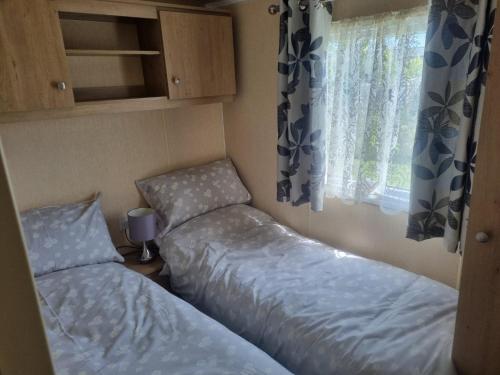 two beds in a small room with a window at 8 BERTH DELUXE PG153 GOLDEN PALM CHAPEL ST LEONARDS in Chapel Saint Leonards