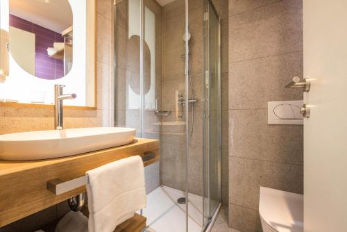 uma casa de banho com um lavatório e um chuveiro em Hotel Vile Park Premium em Portorož