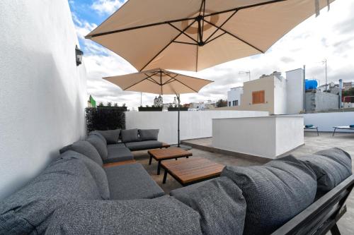 une terrasse avec un canapé, des tables et un parasol dans l'établissement CASA VERDE Comfortable Air-Conditioned Modern Apartments, à Ingenio