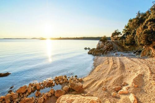 a rocky shoreline with the sun setting over the water at Holiday house Punta Blue & Orange 5m from the sea, island Cres in Punta Križa