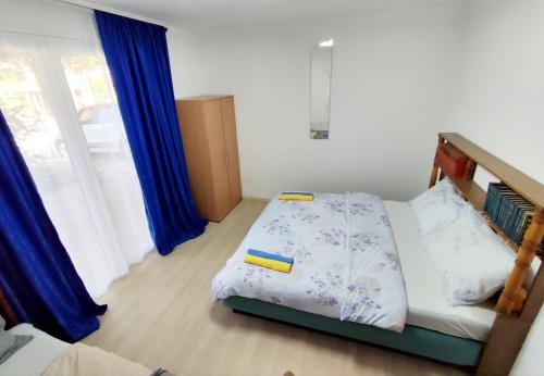 a small bedroom with a bed with blue curtains at Apartments and Rooms Minex in Trebinje