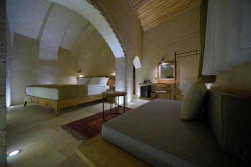 a bedroom with a bed and a couch in a room at Kappadoks Cave Hotel in Uchisar