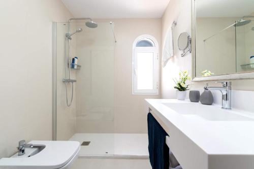 a white bathroom with a sink and a shower at Villa Isabella by Villa Plus in Corralejo