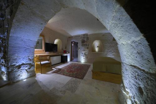 a bedroom with a bed and a desk in a stone wall at Kappadoks Cave Hotel in Uchisar