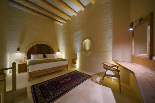 a bedroom with a bed and a chair in a room at Kappadoks Cave Hotel in Uchisar