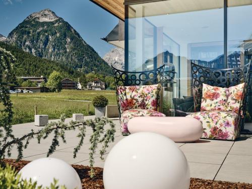 um pátio com 2 cadeiras e vista para uma montanha em Hotel Auszeit em Pertisau