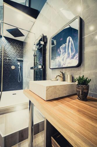 une salle de bain avec un lavabo et un miroir dans l'établissement Le Jardin secret, à Pontoise